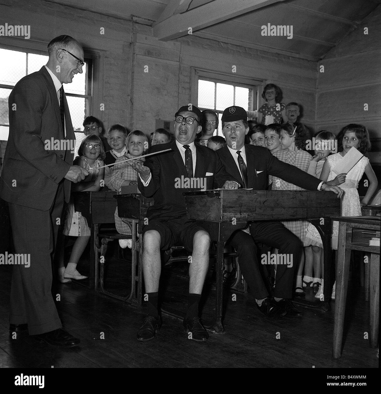 Eric Morecambe Komiker Jul 1962 bekommt den Rohrstock von Schulleiter James W Martin der Ratcliff Sch Stepney London von beobachtet der Stockfoto