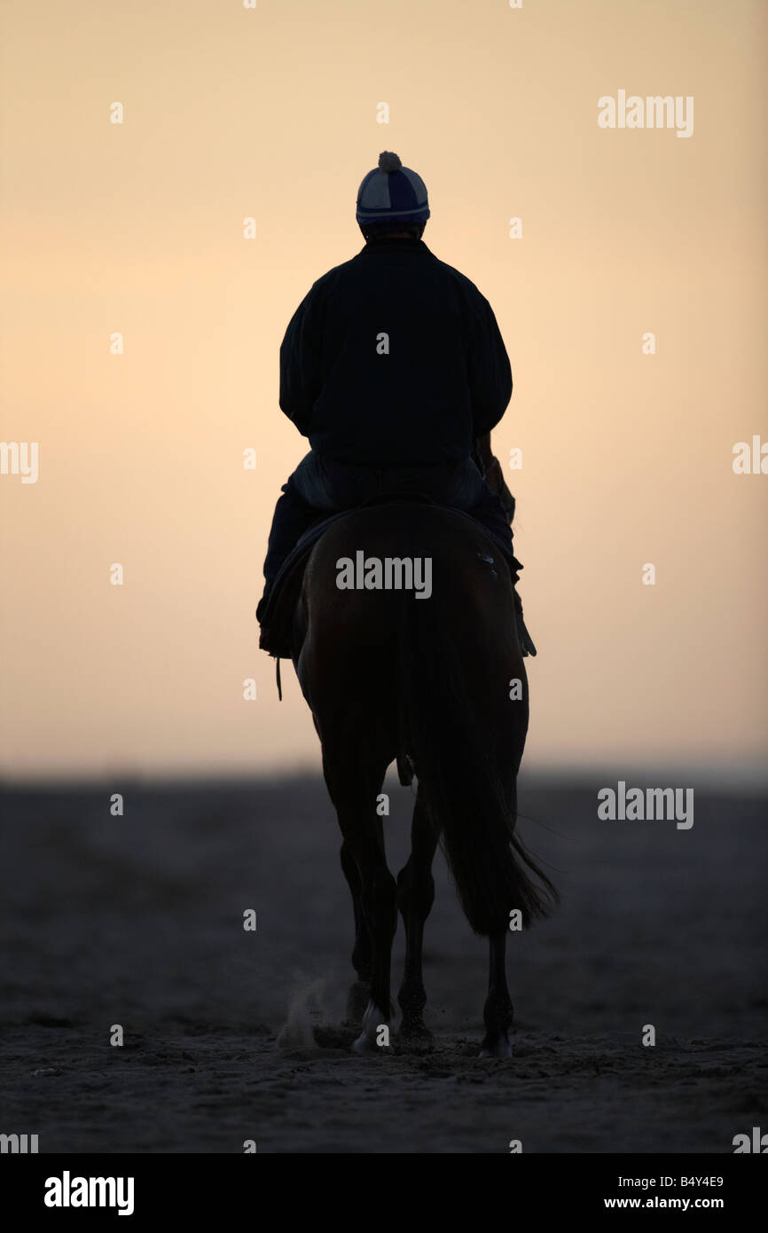 Pferd und Reiter Jockey Wandern entlang dem Strand bei weissen Felsen Portrush bei Sonnenuntergang Nordirland Vereinigtes Königreich Stockfoto