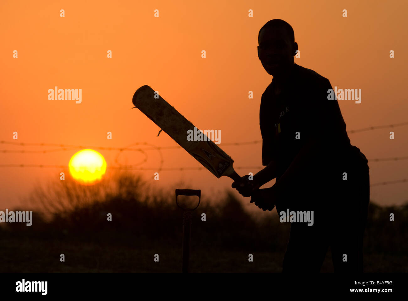 Cricket Spieler Silhouette, Sonnenuntergang, Jugend, Gemeinde, St. Lucia, Kwazulu-Natal, Südafrika Stockfoto