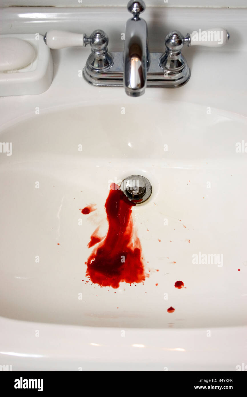 Blut fließt in den Abfluss des Waschbeckens.  Das Blut beginnt zu gerinnen in der Spüle. Stockfoto