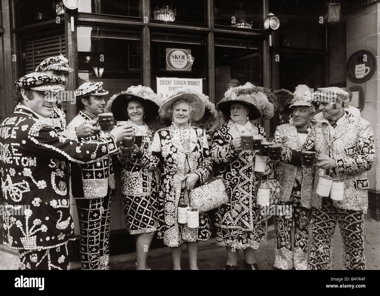 Pearly Kings und Queens feiern Covent Gardens 300. Geburtstag Costers Hüte Tasten halten Bier Gläser sammeln Zinn Charity Toast trinken Pub Custom London Männer Frauen Cheers kann 1970 1970s Mirrorpix Everettselected Stockfoto