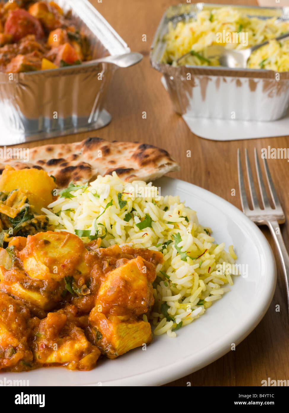 Platte aus Indian Take Away Chicken Bhoona, Sag Aloo, Pilau Reis und Naan-Brot Stockfoto