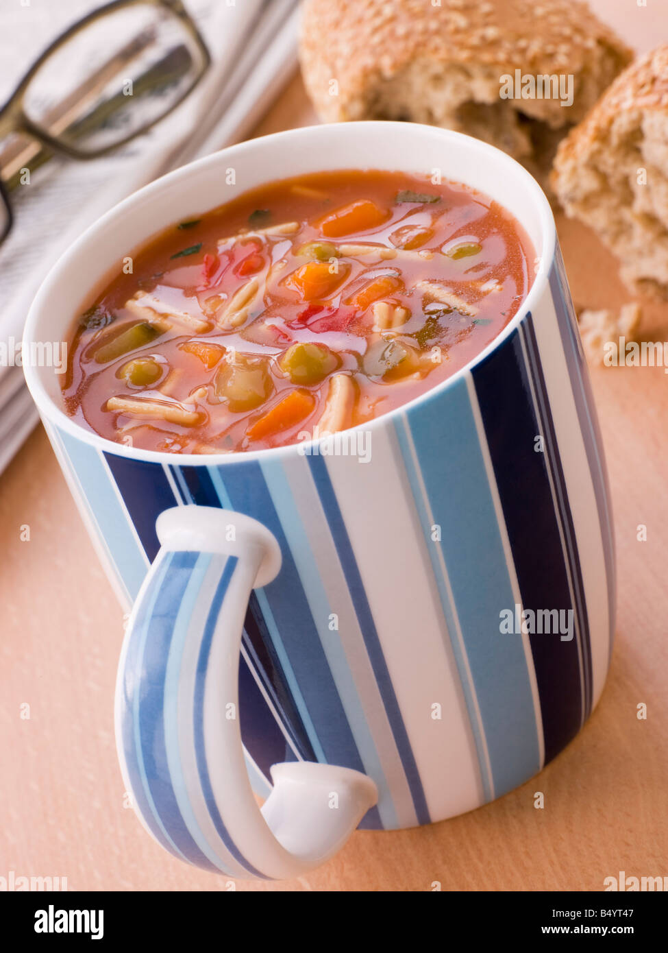 Tasse Gemüse und Nudeln Suppe mit einem Getreidespeicher Brötchen Stockfoto
