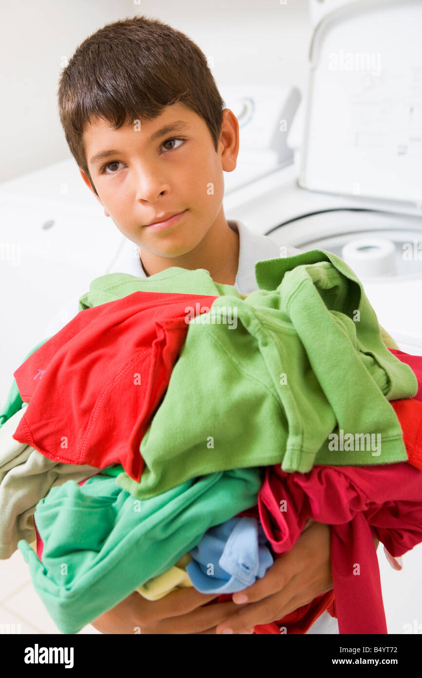 Kleiner Junge hält einen Haufen Wäsche Stockfoto