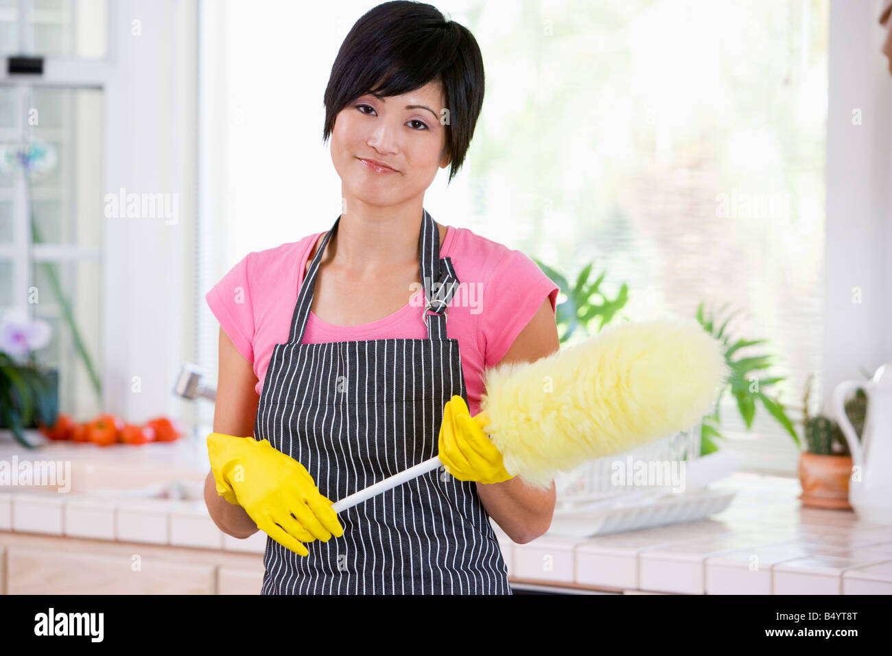 Frau mit Duster und Gummihandschuhe tragen Stockfoto