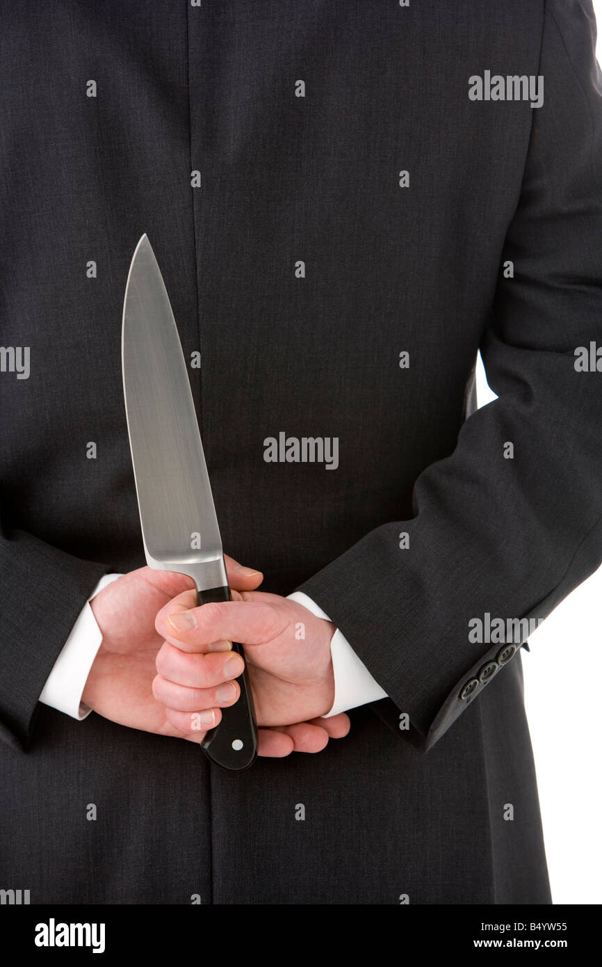 Geschäftsmann mit Messer hinter seinem Rücken Stockfoto