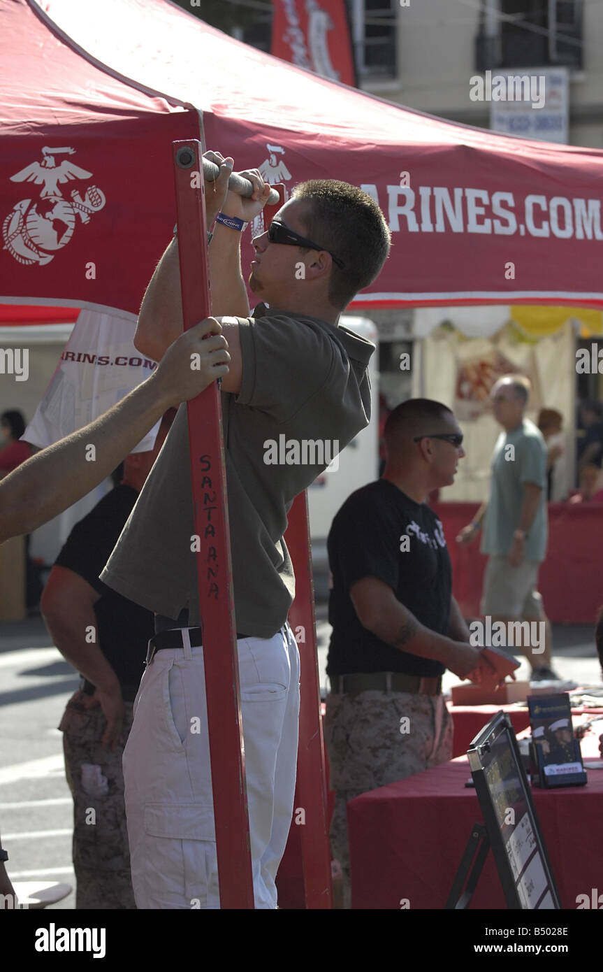 Besucher zu einem US Marine Corps recruiting Stand auf einer Straße Messe demonstrieren ihre Pull-up-Fähigkeiten Stockfoto