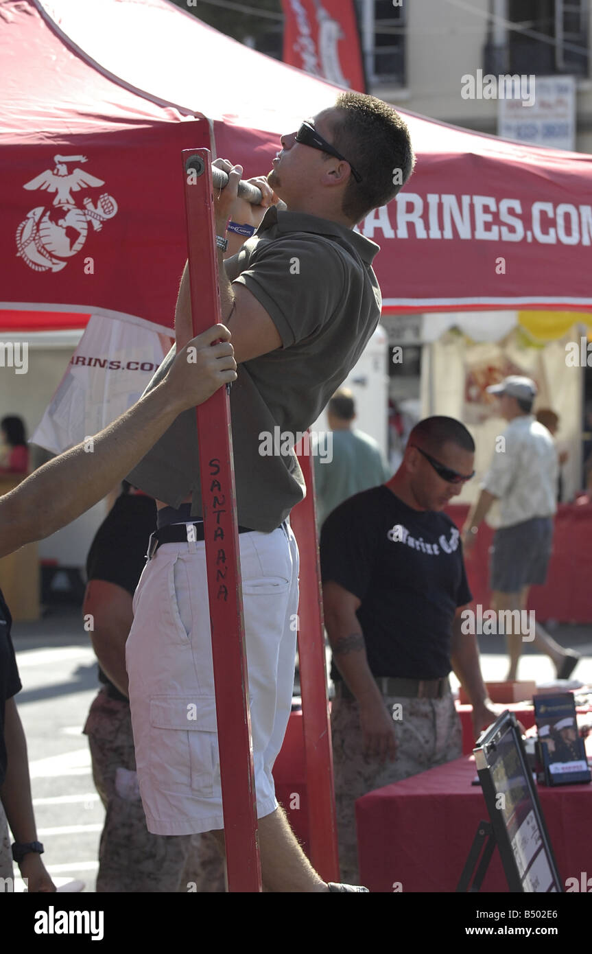 Besucher zu einem US Marine Corps recruiting Stand auf einer Straße Messe demonstrieren ihre Pull-up-Fähigkeiten Stockfoto