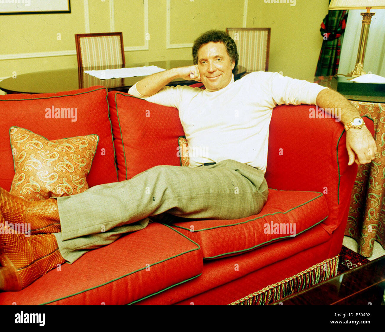 Tom Jones Sanger Auf Britischen Tour Sitzen Auf Roten Sofa Arm Am Rucken Kopf Auf Hand Weissen Rollkragen Stockfotografie Alamy