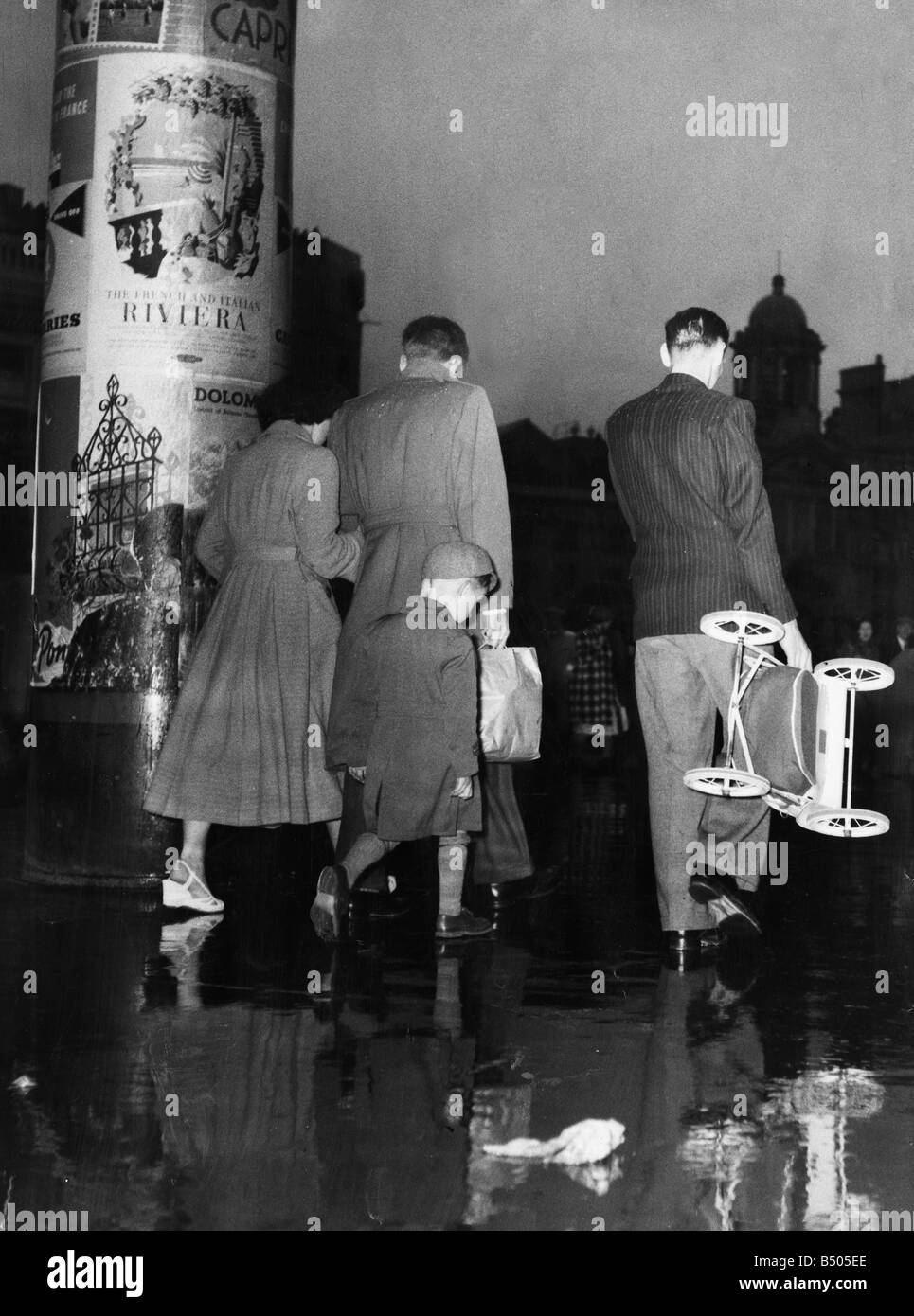 Einem regnerischen fertig stellen, um ein nasses Whit Wochenende war zumindest das Gebot der Stunde, in London. Eine Poster bedeckt Spalte außerhalb Victoria Station Werbung ausländischer Urlaub und Reisen, war die hellste Gruß an den wiederkehrenden Urlaubern.; Juni 1954 Stockfoto