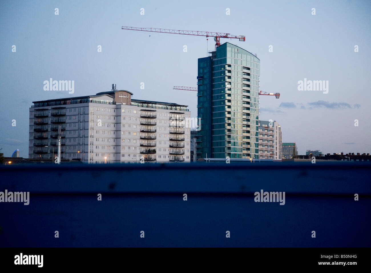 Hochhäuser im East End über den oberen Teil der blauen Zaun laufen rund um die Baustelle der Olympischen Spiele in London zu sehen. Stockfoto