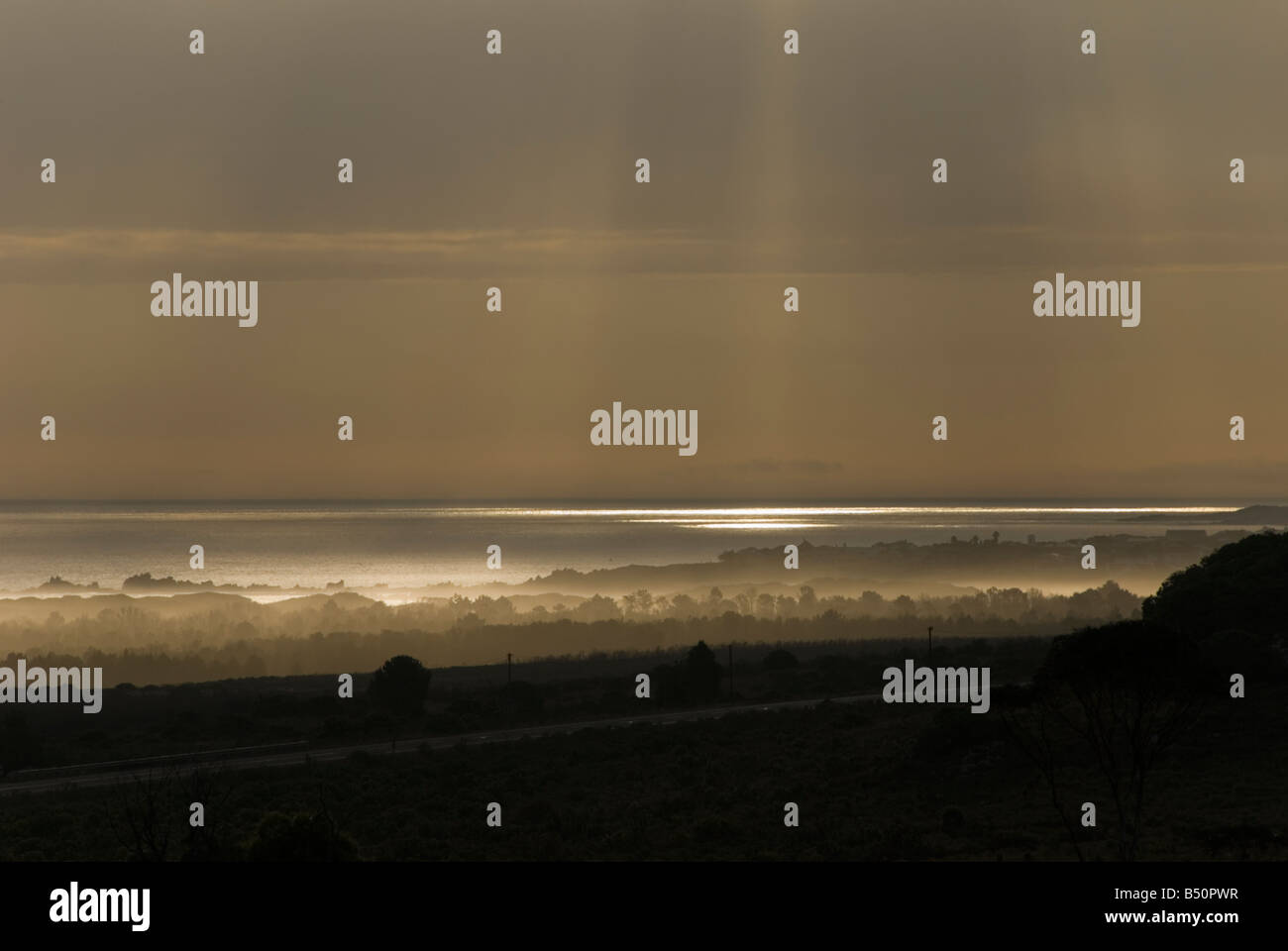 Himmlische Sonnenstrahlen durchbrechen Wolken und Licht auf dem Wasser. Wellen von Licht reflektieren und schimmern auf den Ozean. Stockfoto