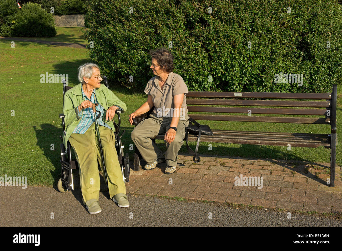 Mittelalter Frau mit Seniorin im Rollstuhl sitzen, reden im park Stockfoto