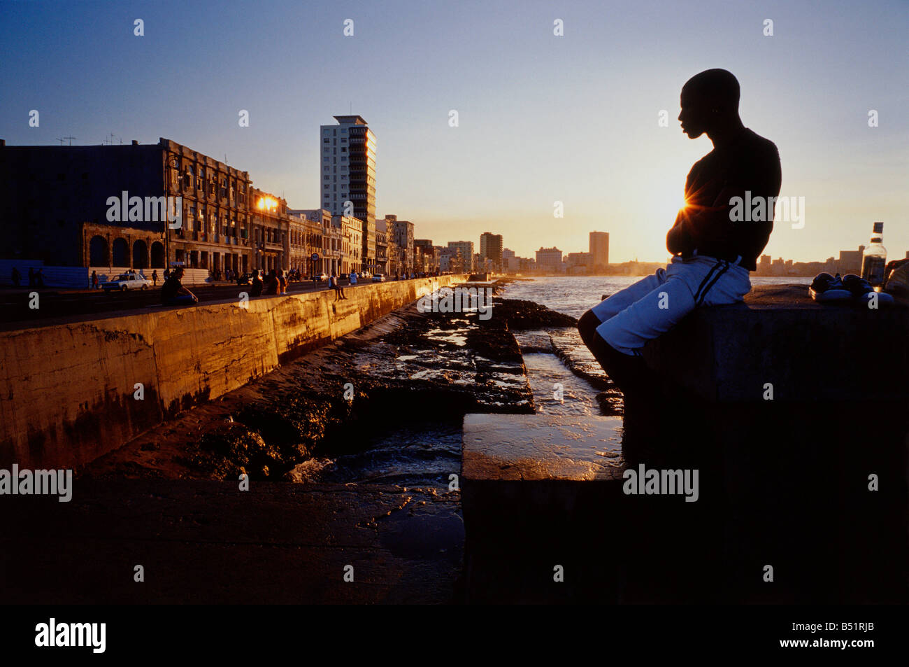 Mann, sitzend von Wasser bei Sonnenuntergang Malicon, Havanna, Kuba Stockfoto