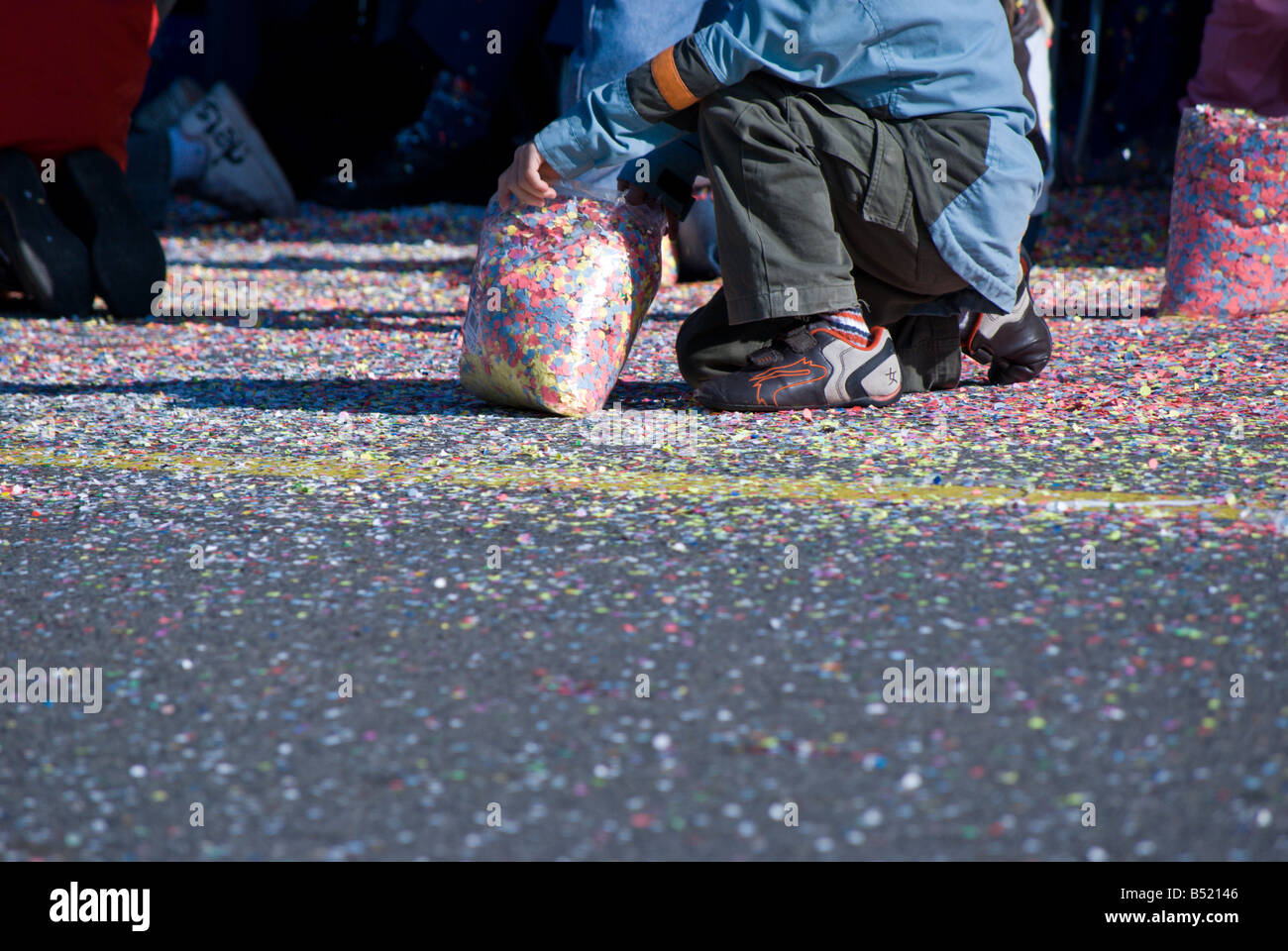 Ein Kind sammelt Konfetti aus dem Boden bei der Fête des Vendanges Stockfoto