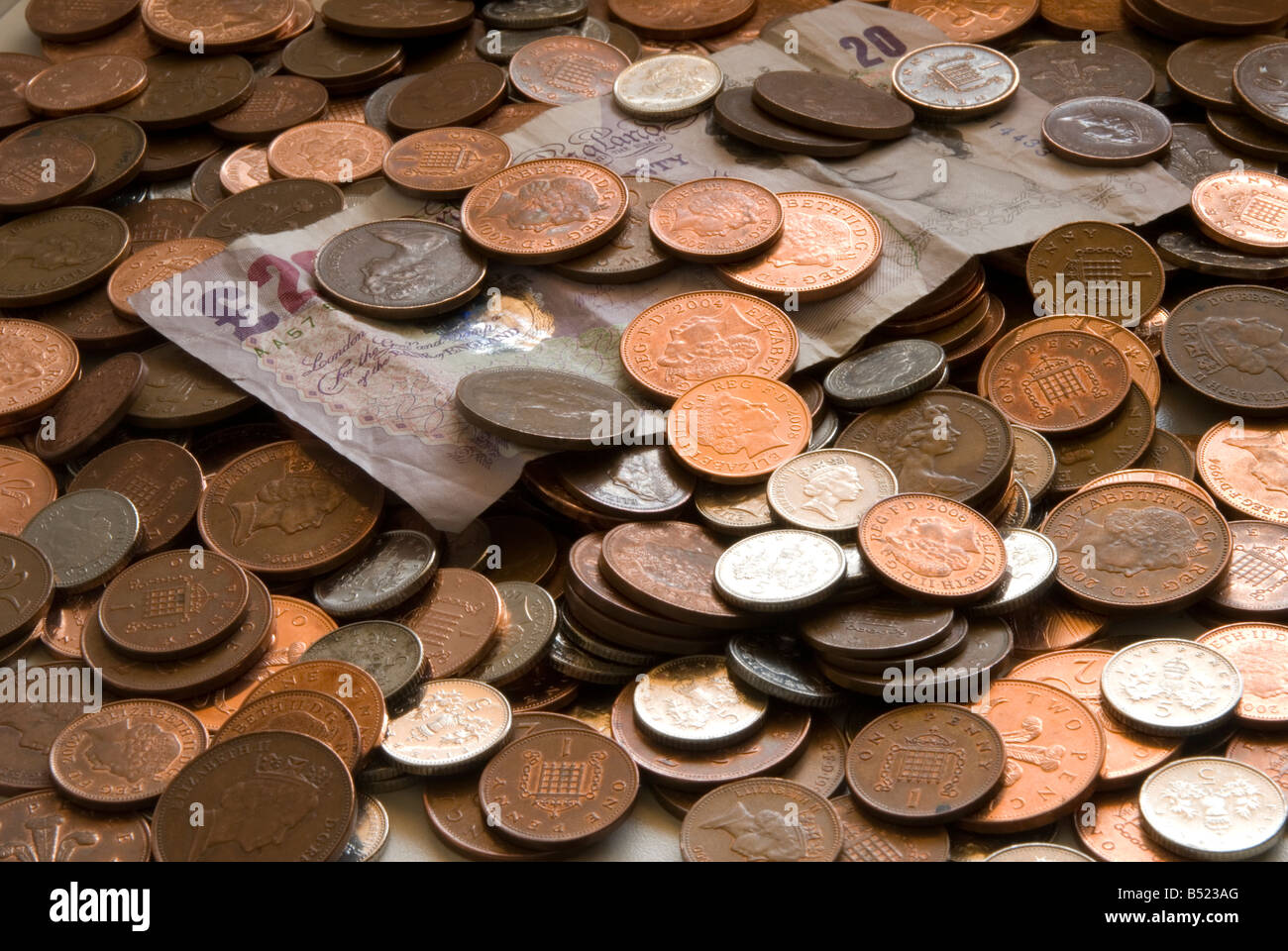 Münzen und zwanzig Pfund-note Stockfoto