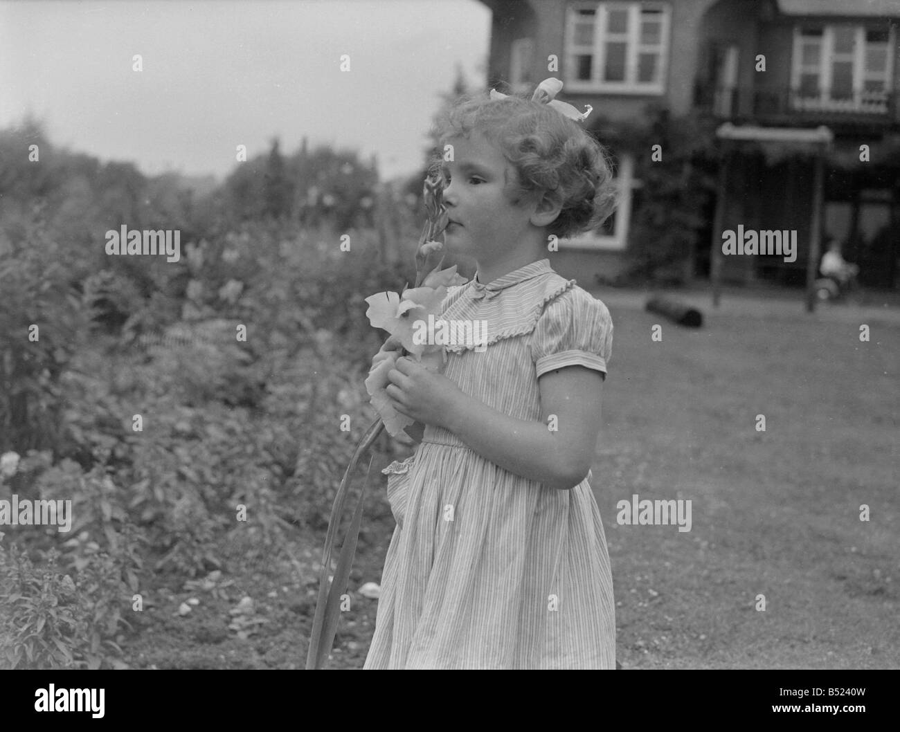 Kinder bei Sonnenschein zu Hause für blinde Kinder. "Sheila" 5 yr alten blinden Kind riecht den Duft der Gladiolen Blume. Um 1950 Stockfoto
