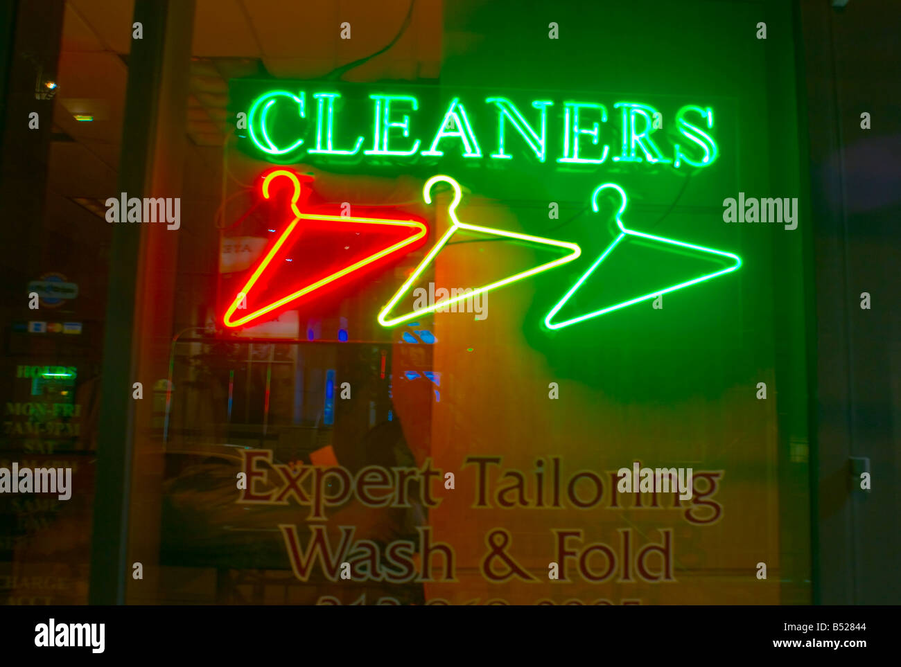 Drei Neon-Kleiderbügel in NYC Reinigungen Wäscherei speichern Fenster. Stockfoto