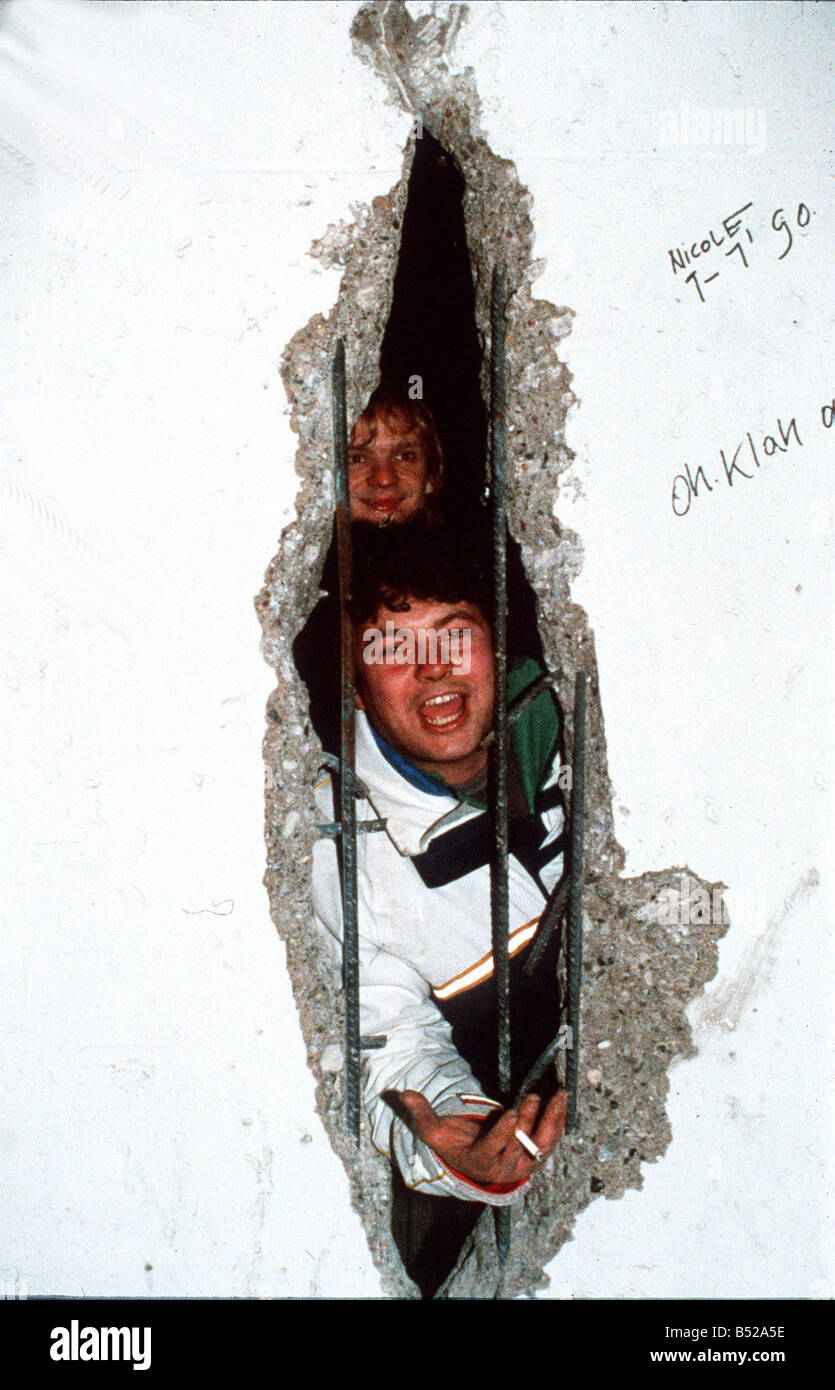 Silvester in Berlin 1990 mit einem neuen Blick aus dem Osten durch ein Loch in die Berliner Mauer Y2K Politik Y2K Protest gebaut der DDR im Jahr 1961, eine Flut von Flüchtlingen vom Kommunismus zu stoppen, die Mauer zwischen Berlin die Eisernen Vorhangs folgenden wachsenden Krisen in den 80er Jahren in der UdSSR und verzweifelten Bemühungen zur Reform ostdeutschen Staats-und Regierungschefs versprochen, dass die Freizügigkeit von 10. November 1989 um Mitternacht auf die 9. Tausende begann verkörpert hatte durch Gießen die Kontrollpunkte von beiden Seiten Klettern und tanzen an der Wand und Hacken dabei, der Auftrag von Bulldozern und abgeschlossen wurde, innerhalb eines Jahres Stockfoto