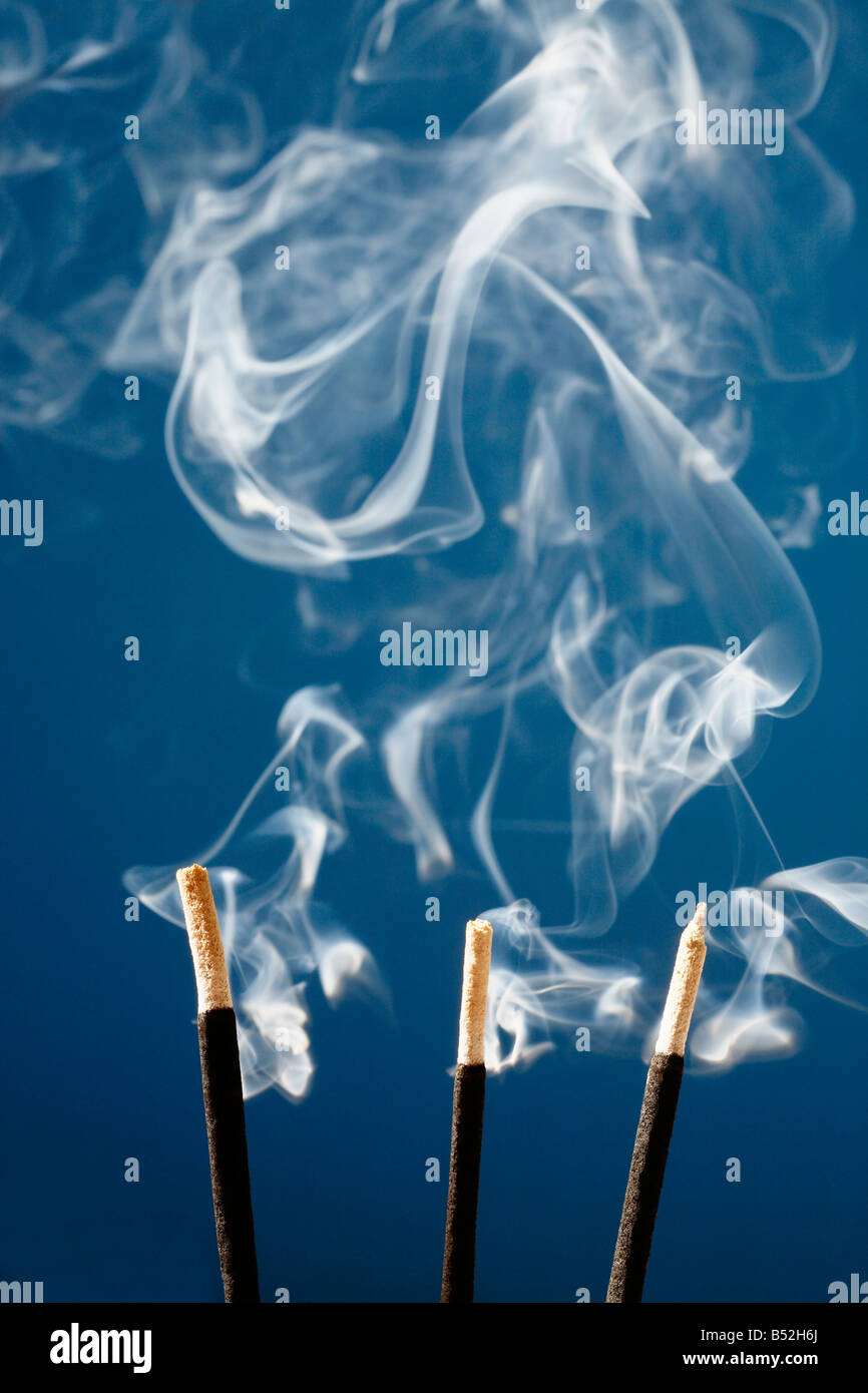 Drei brennende Räucherstäbchen Stöcke und weißer Rauch Stockfoto