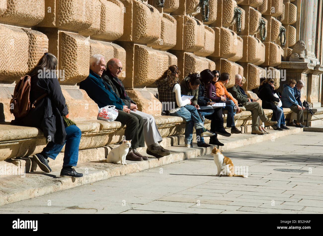 Touristen, Aufwärmen im Wintersonne vor dem Carlos V Palast an der Alhambra, Granada, Spanien Stockfoto