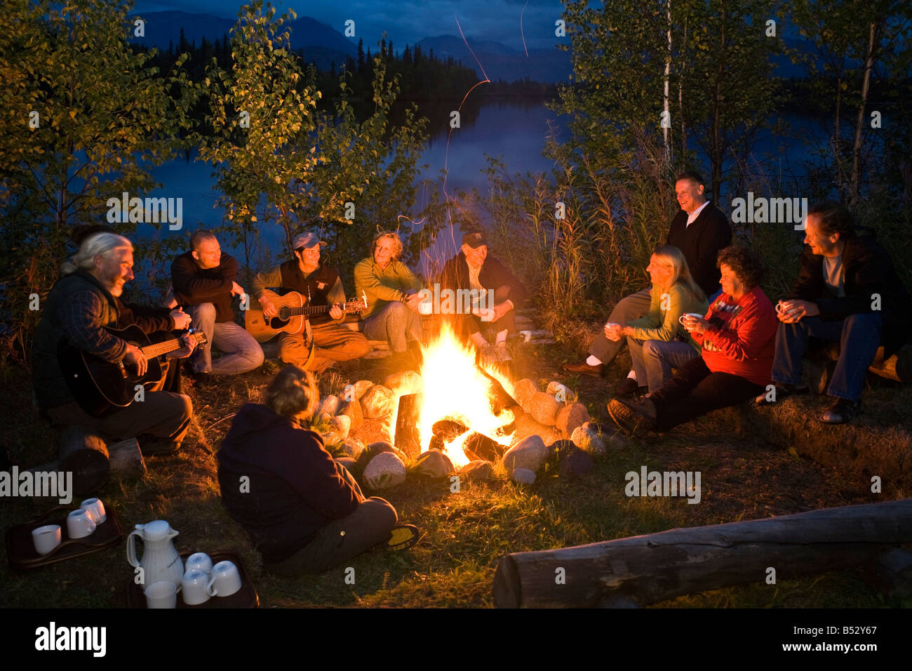 Gruppe von Erwachsenen sitzen um ein Lagerfeuer im Winter Gruppe von Erwachsenen sitzen um ein Lagerfeuer im Winter