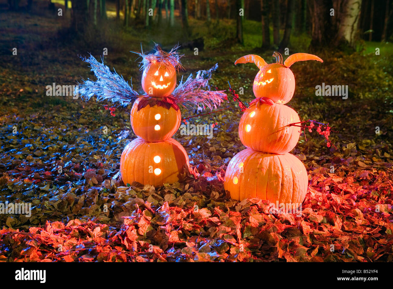 Jack-O-Laterne zu zweit, ein Engel & ein Teufel, stehend in einem Wald & Laub in der Dämmerung, Herbst Anchorage, Alaska. Stockfoto