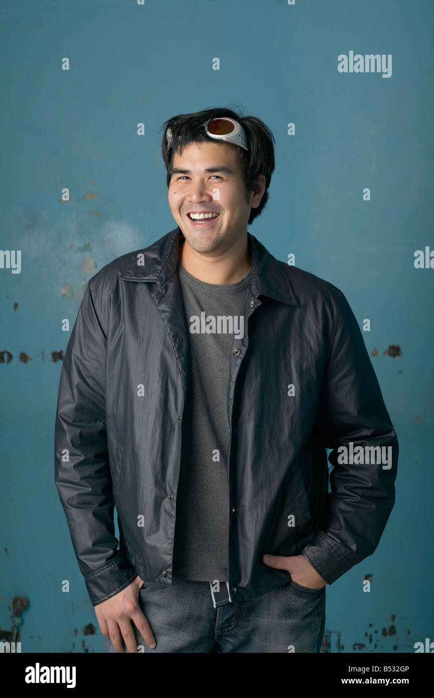 Asiatischer Mann lächelnd mit Händen in den Taschen Stockfoto