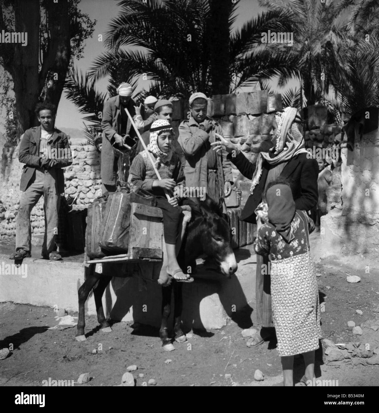 Eine arabische Frau spricht mit einer Gruppe junger Männer in der Trans - Jordanien Stadt Aqaba. März 1952 C1288 Stockfoto