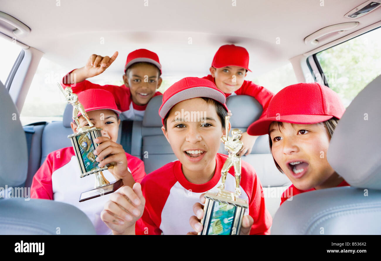 Multi-ethnischen Jungs im Auto Baseball Uniformen trägt und hält Trophäen Stockfoto