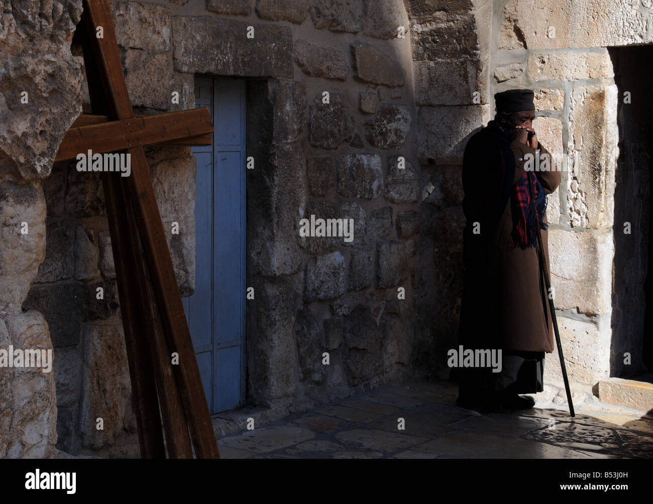 Ein äthiopischer Priester steht ruhig im Rathaushof beeindruckend von der Auferstehungskirche in der Jerusalemer Altstadt. Stockfoto