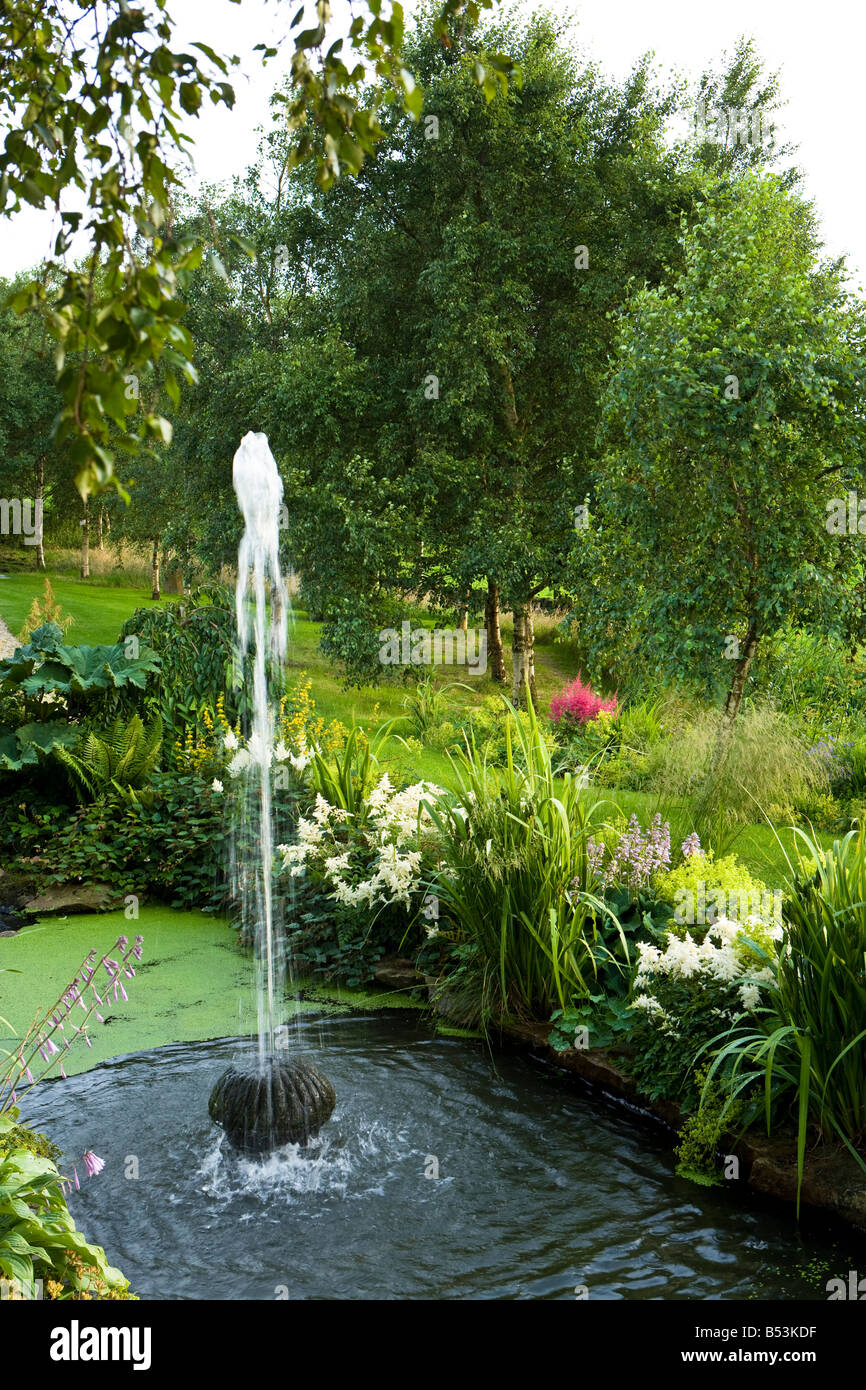 Brunnen in einem Teich mit astilbes Stockfoto