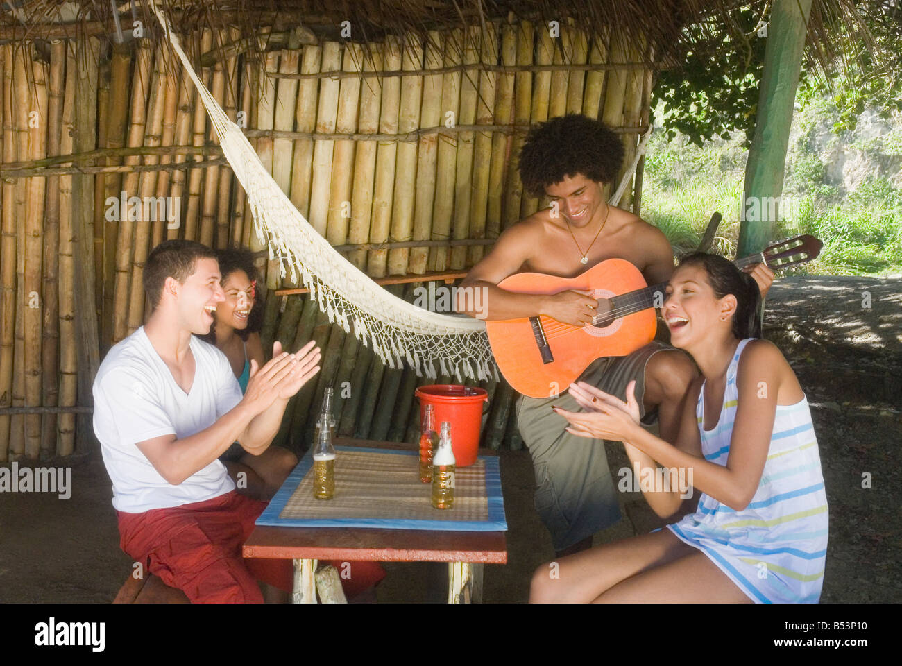 Freunde hören Mann spielen Gitarre Stockfoto