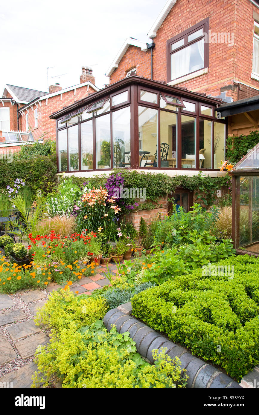 Rückseite des großen Einfamilienhaus mit Wintergarten und gut bepflanzten Garten Stockfoto