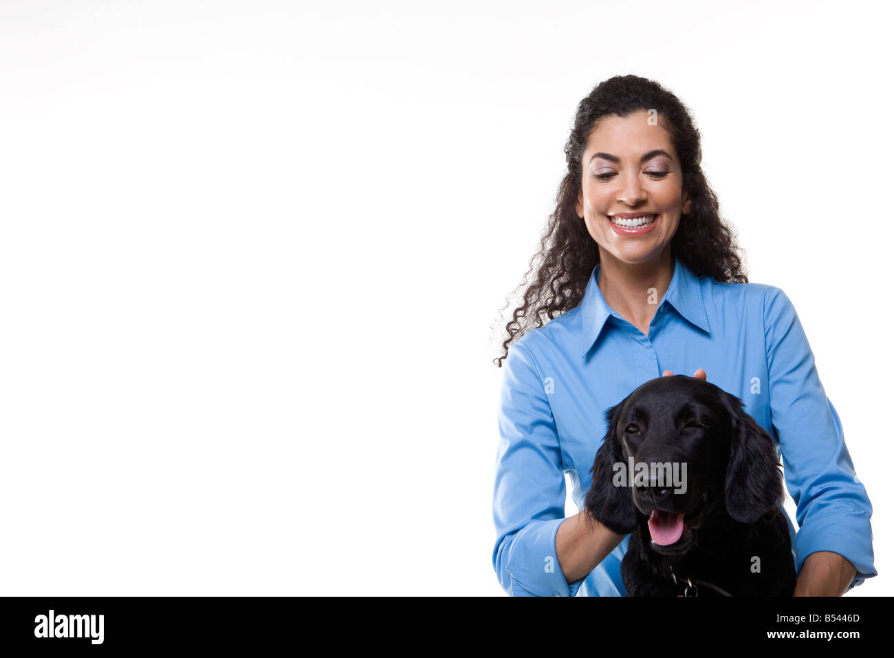 Frau spielt mit einem schwarzen Hund auf weißem Hintergrund Stockfoto