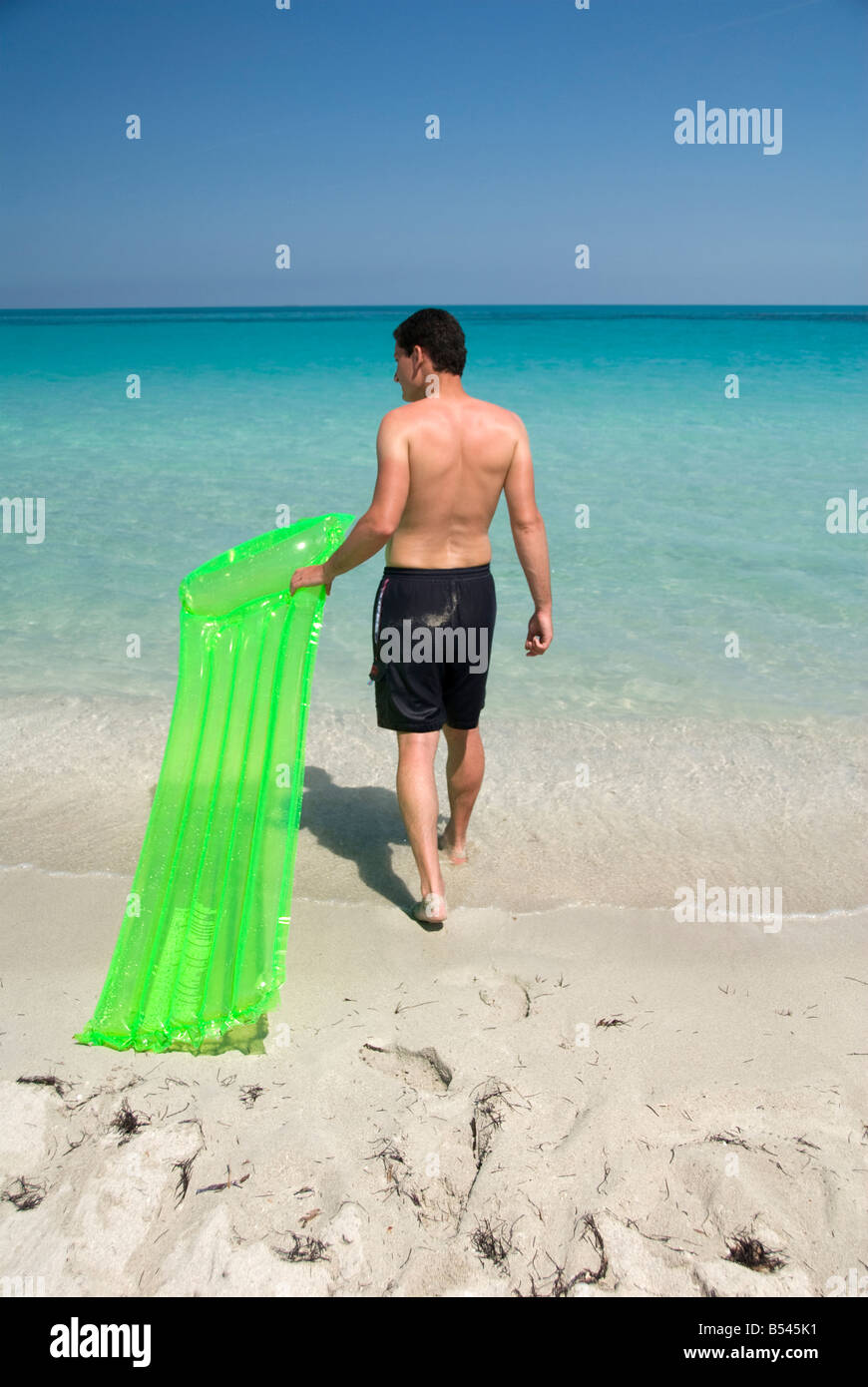 Ein Mann mit Luftmatratze am Strand Stockfoto
