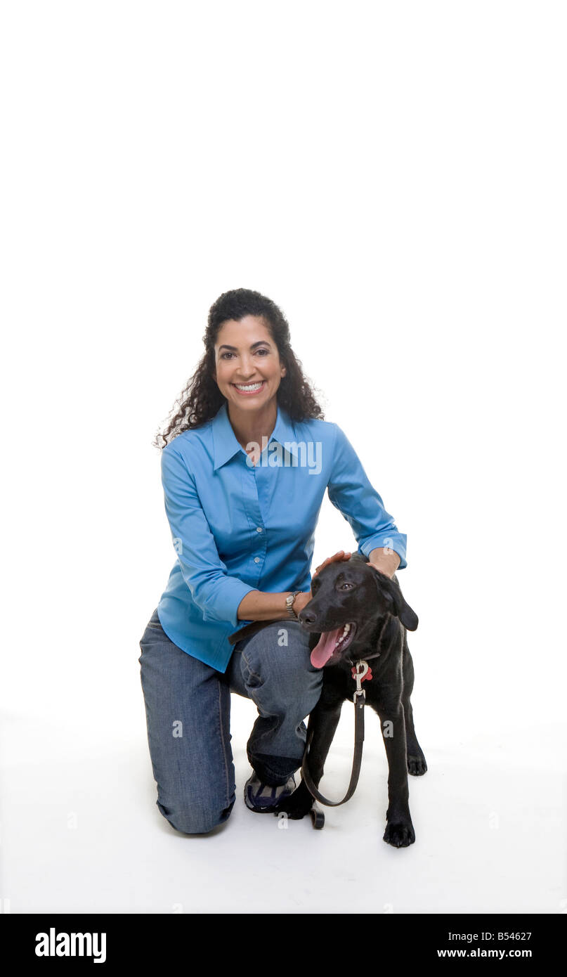 Glücklich Latina Frau Haustiere Hund angeleint während sie kniet Stockfoto