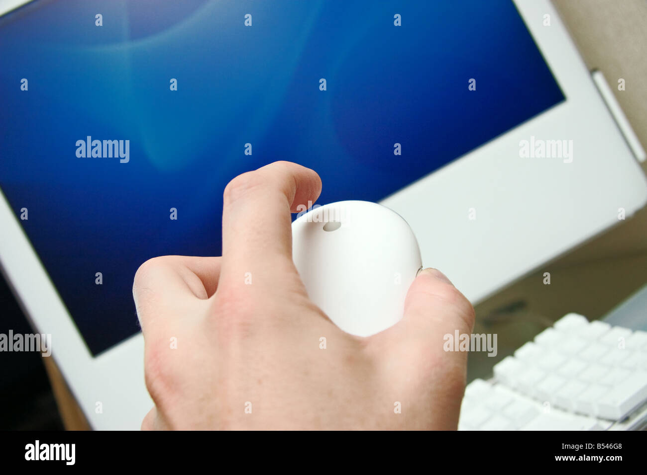 Mans Hand mit Apple Maus über Luft-Bildschirm des iMac-Computer auf eine Kulissen ausgewählte Fokus auf eine Kugel und finger Stockfoto