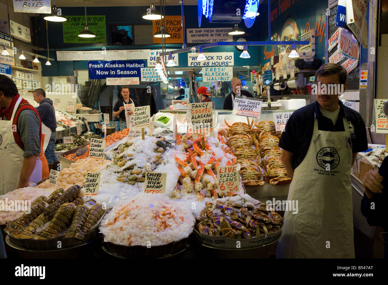 Männer verkaufen Meeresfrüchte auf dem Pure Food Fischmarkt am Pike Place Market in Seattle, Washington, USA Stockfoto