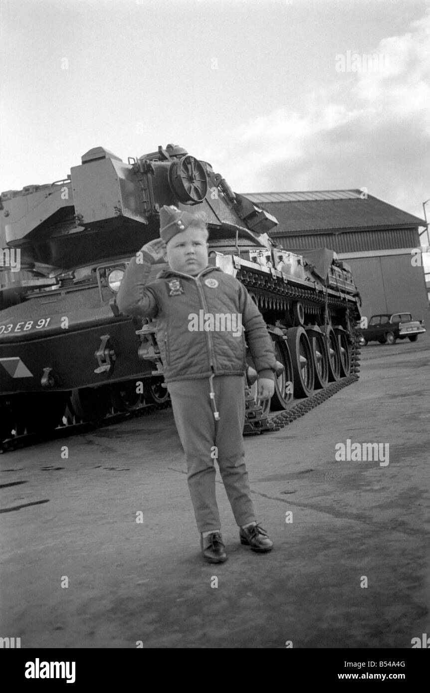 Kinder Humor militärische. Sechs Jahre alten Jungen tragen eine Armee Kappe und Abzeichen Gires ein Gruß, wie er vor einem britischen Chieftain Tank steht. November 1969 Z10765 Stockfoto
