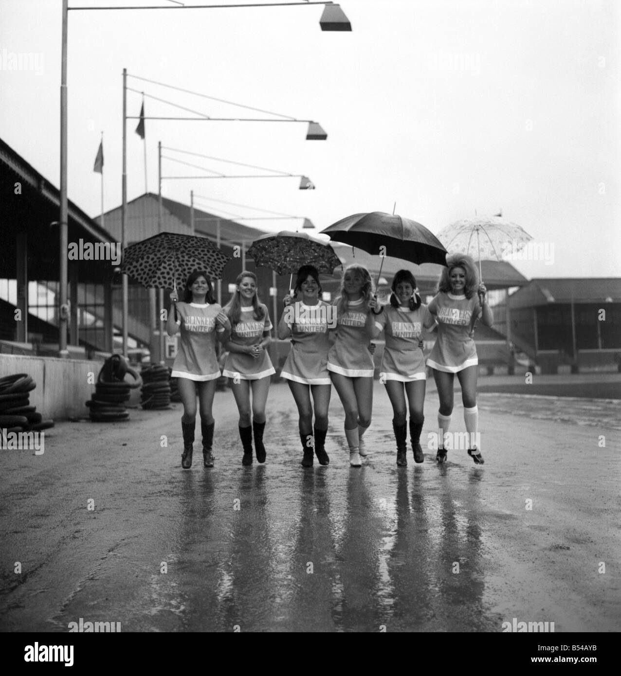 Aufgereiht in ihren Mini-Fußball-Kleidern auf was sollte die Zeit zum Anpfiff sind 6 der Scheuklappen Utd Fußball-Nationalmannschaft gewesen. Die Scheuklappen Utd V alle Sterne XI Fußball Benefizspiel hatte abgesagt, nachdem entschieden wurde, dass das Wetter nicht geeignet war, zu spielen. Als die Männer beobachtete lief die Mädchen rund um den Boden zu Manchesters Belle Vue tragen Regenschirme, um ihr Haar zu schützen. ; November 1969; Z10898-001 Stockfoto
