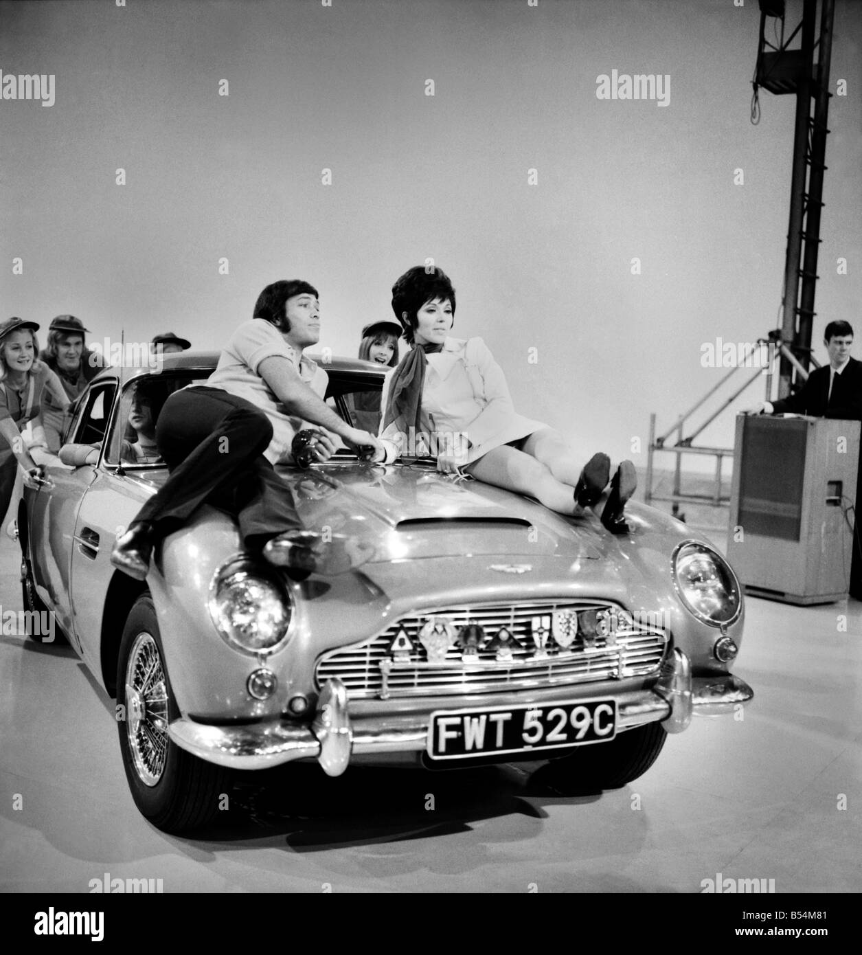 Sängerin Susan Maughan am Set von The Samstag Crowd im Weekhand Studio London, Wembley aufgenommen. Susan in einem Shateh mit Peter Goggino auf der Motorhaube eines Sportwagens von Aston MArtin. November 1969 Z11306-005 Stockfoto