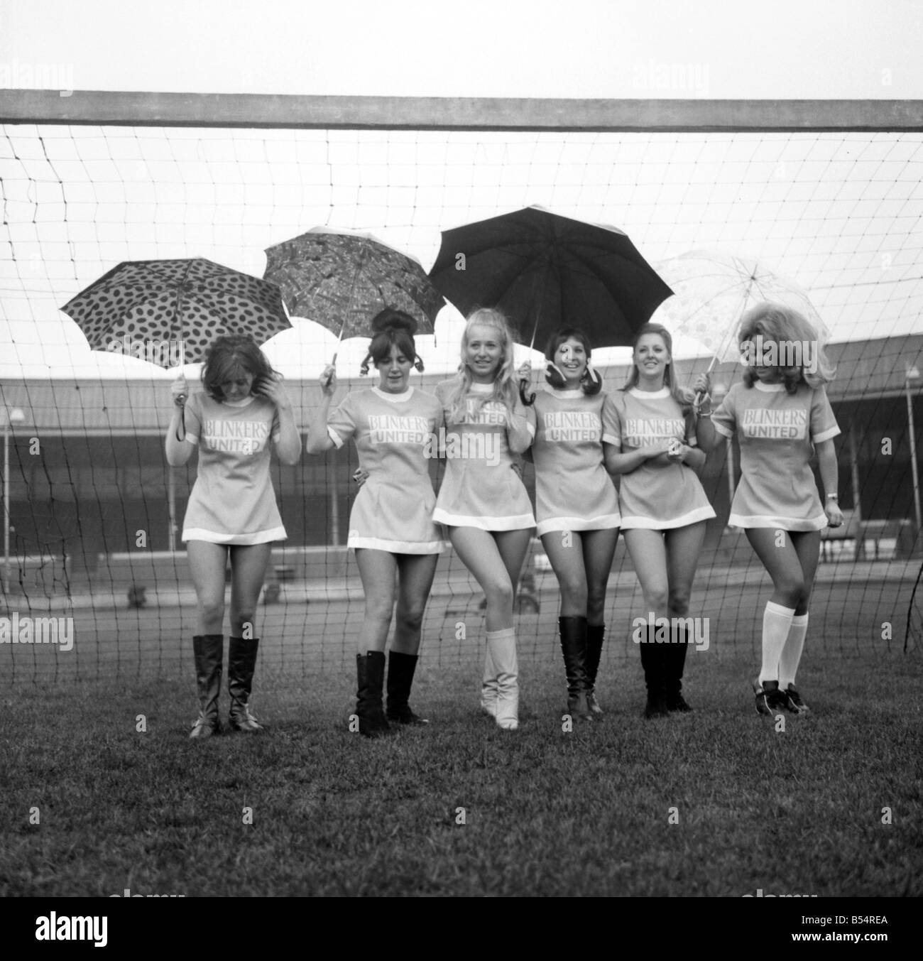 Aufgereiht in ihren Mini-Fußball-Kleidern auf was sollte die Zeit zum Anpfiff sind 6 der Scheuklappen Utd Fußball-Nationalmannschaft gewesen. Die Scheuklappen Utd V alle Sterne XI Fußball Benefizspiel hatte abgesagt, nachdem entschieden wurde, dass das Wetter nicht geeignet war, zu spielen. Als die Männer beobachtete lief die Mädchen rund um den Boden zu Manchesters Belle Vue tragen Regenschirme, um ihr Haar zu schützen. November 1969 Z10898-002 Stockfoto