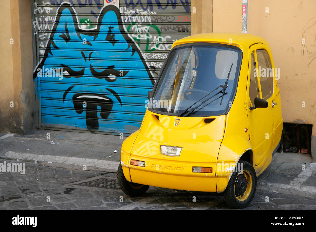 Kleine gelbe Pasquali Riscio Auto und Graffiti Garagentor Stockfoto