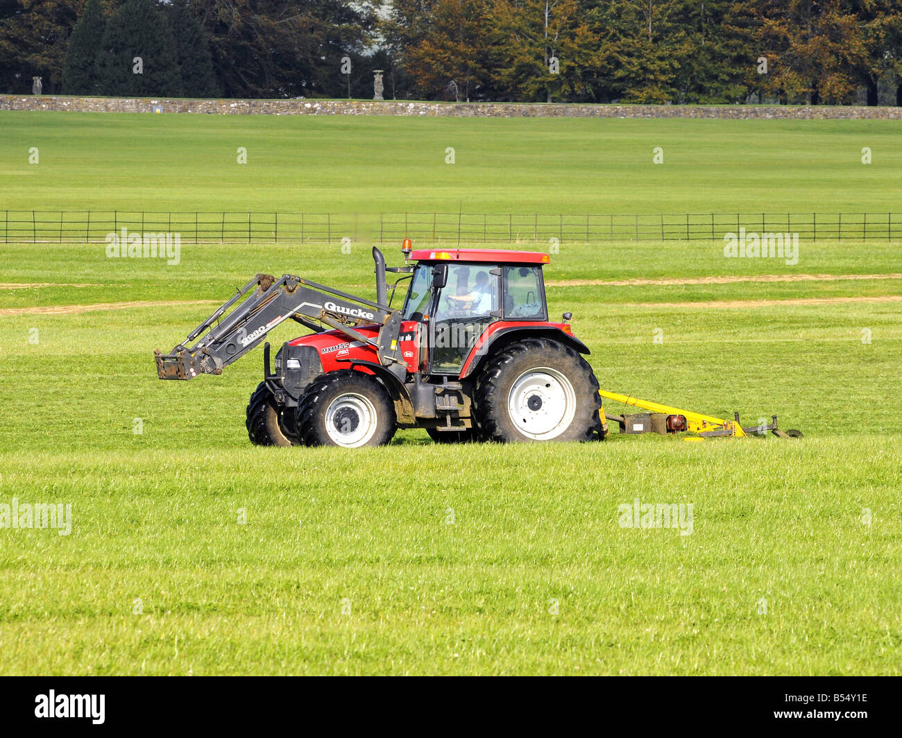 Red Farm Traktor Abschleppen eine große Mähwerk Stockfoto