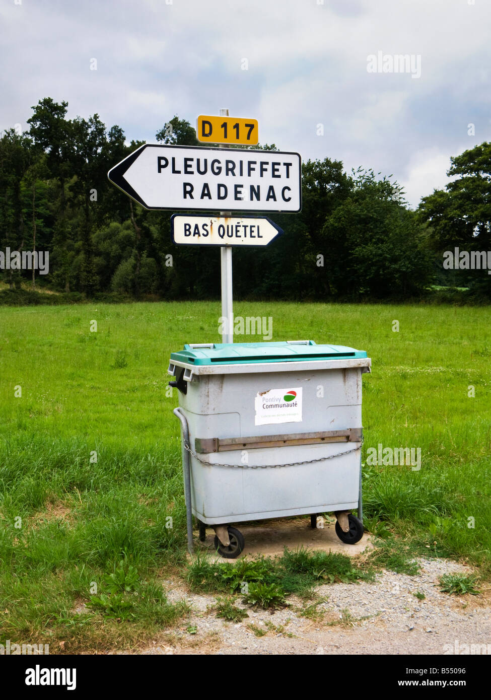 Kommunaler Abfalleimer, poubelle, am französischen Straßenrand im ländlichen Frankreich neben einem lokalen Straßenschild Stockfoto