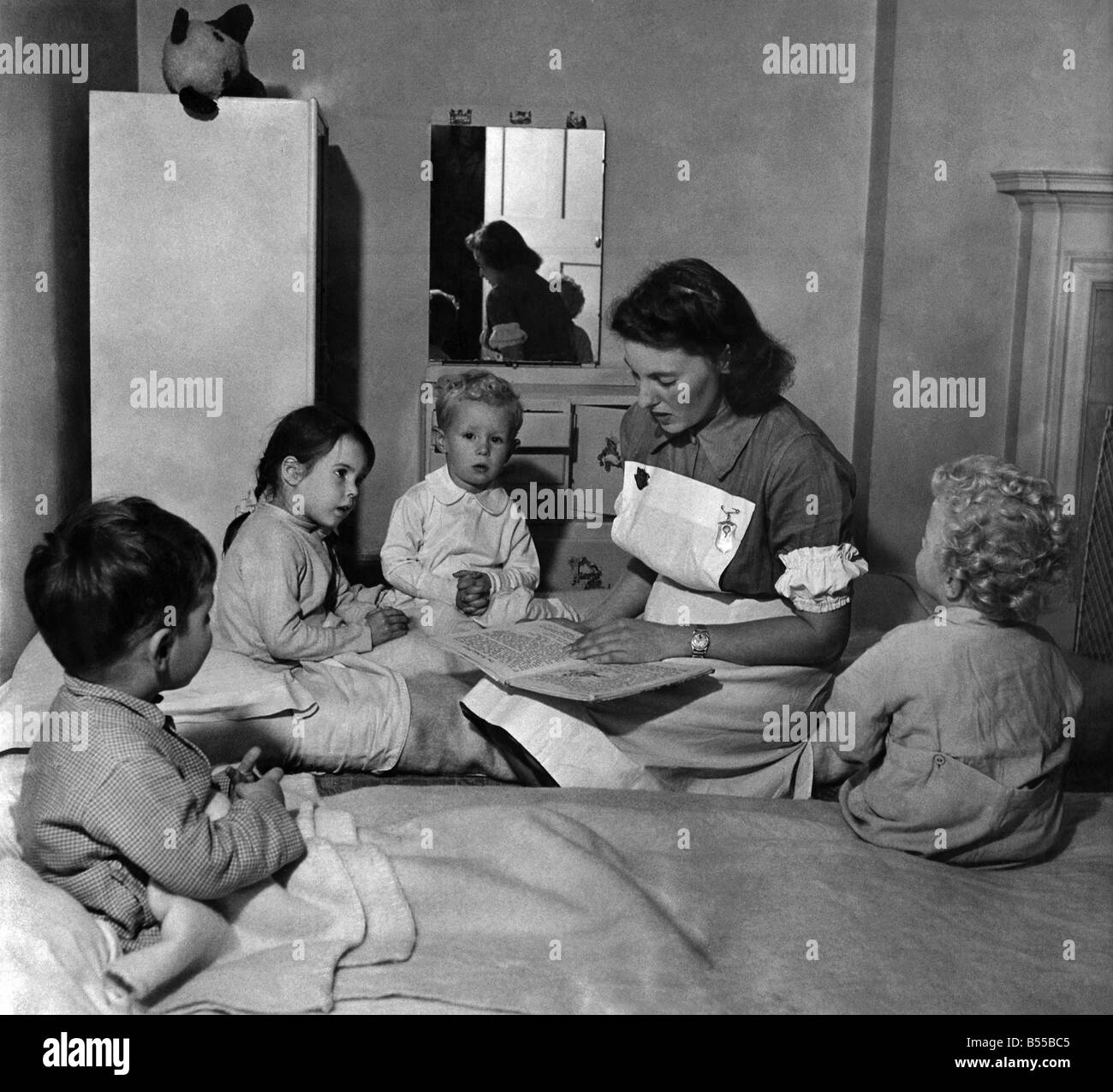 Oberin Doris Naughten liest einige Märchen (links nach rechts) Nigel Paneth, Susan Conen, ein amerikanisches Kind, Christopher Buckmaster und Paul Ganjou, bevor sie zu Bett gehen. Oktober 1949 P012144 Stockfoto