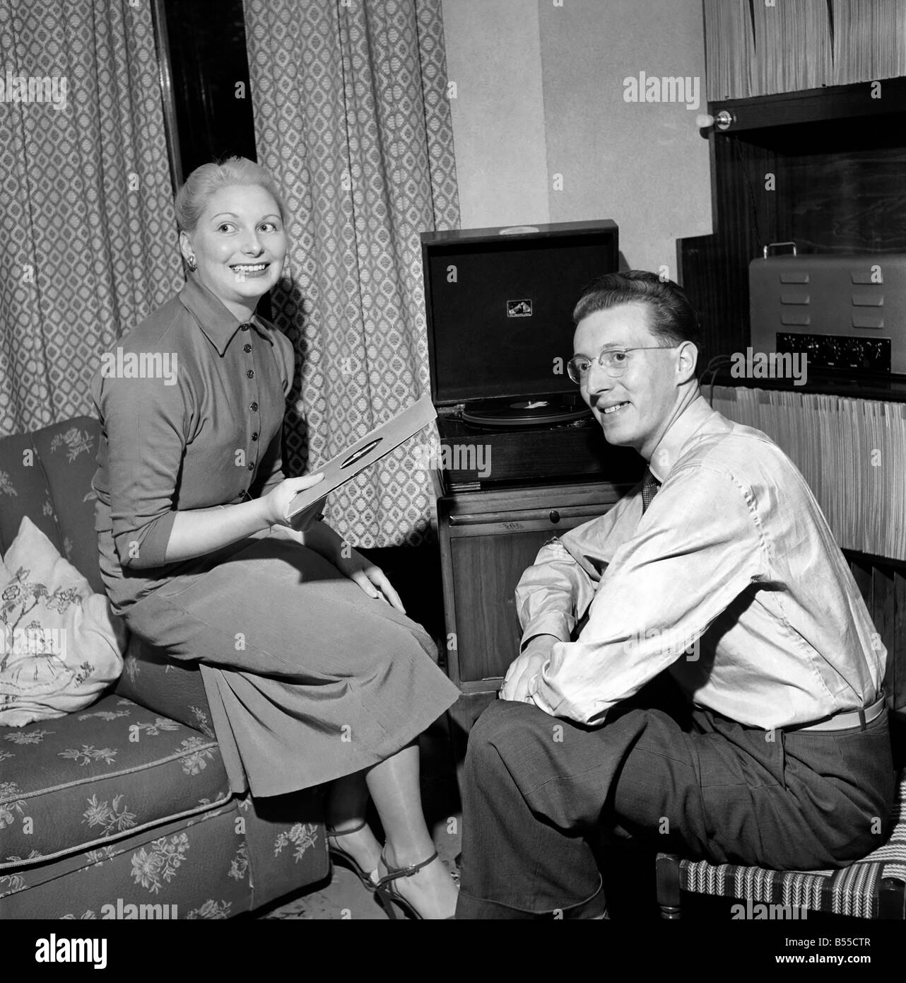 Mann und Frau sitzen und hören Sie Musik auf ihrem Plattenspieler. September 1953 D5574 Stockfoto