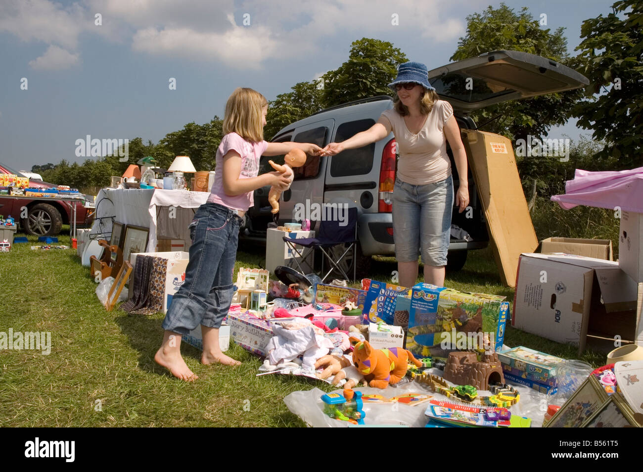 Junges Mädchen (6/7) Kauf einer Puppe auf einem Flohmarkt in UK Stockfoto