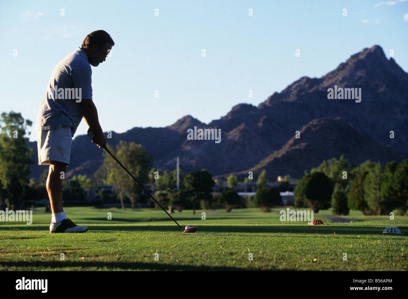 Ein Golfer über t-off auf einer bewässerten Golfplatz in Arizona Wüste, Arizona, USA Stockfoto